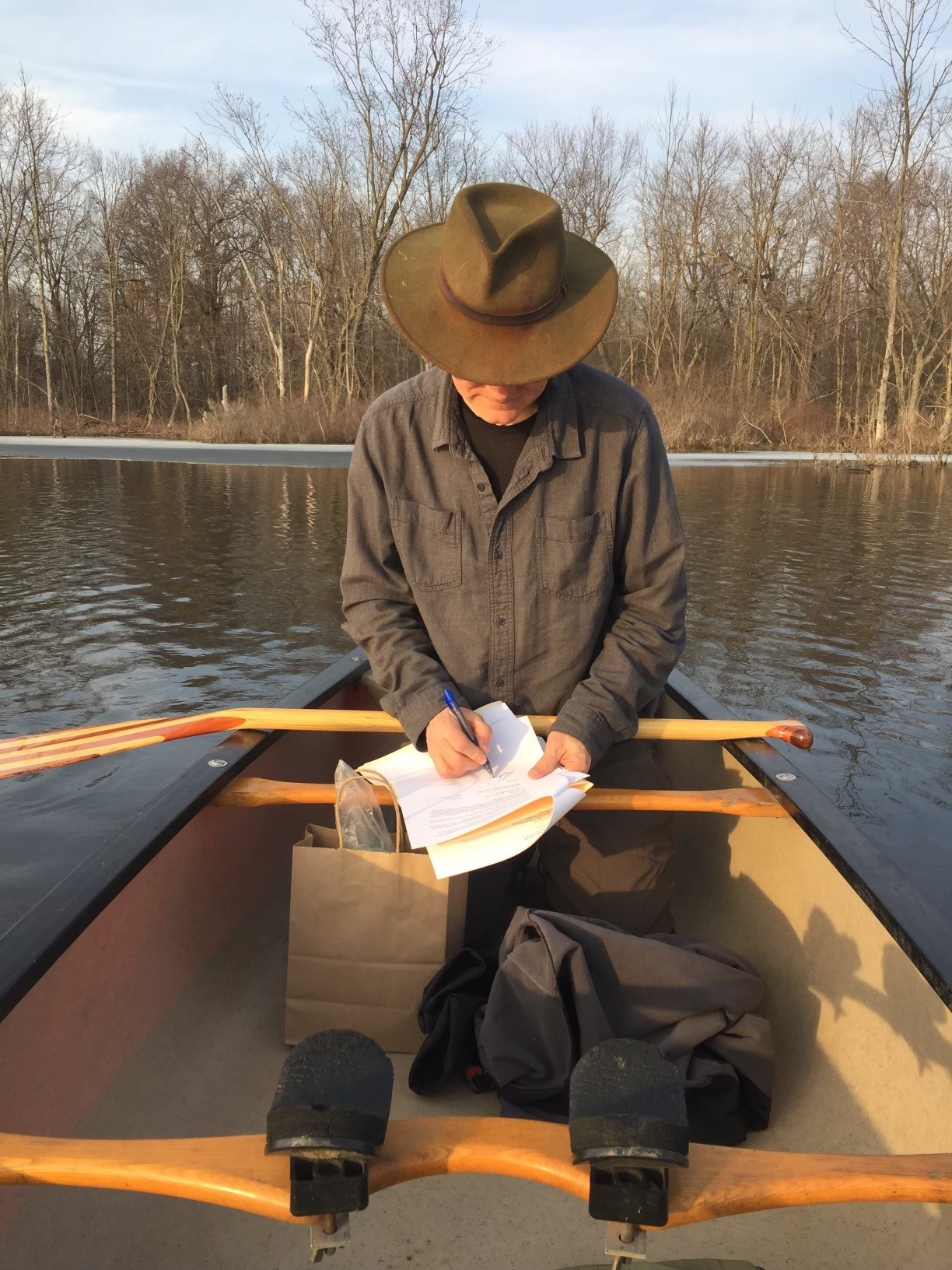 Aron signs his offer letter on the Looking Glass River. Photo credit: Alice Dreger.