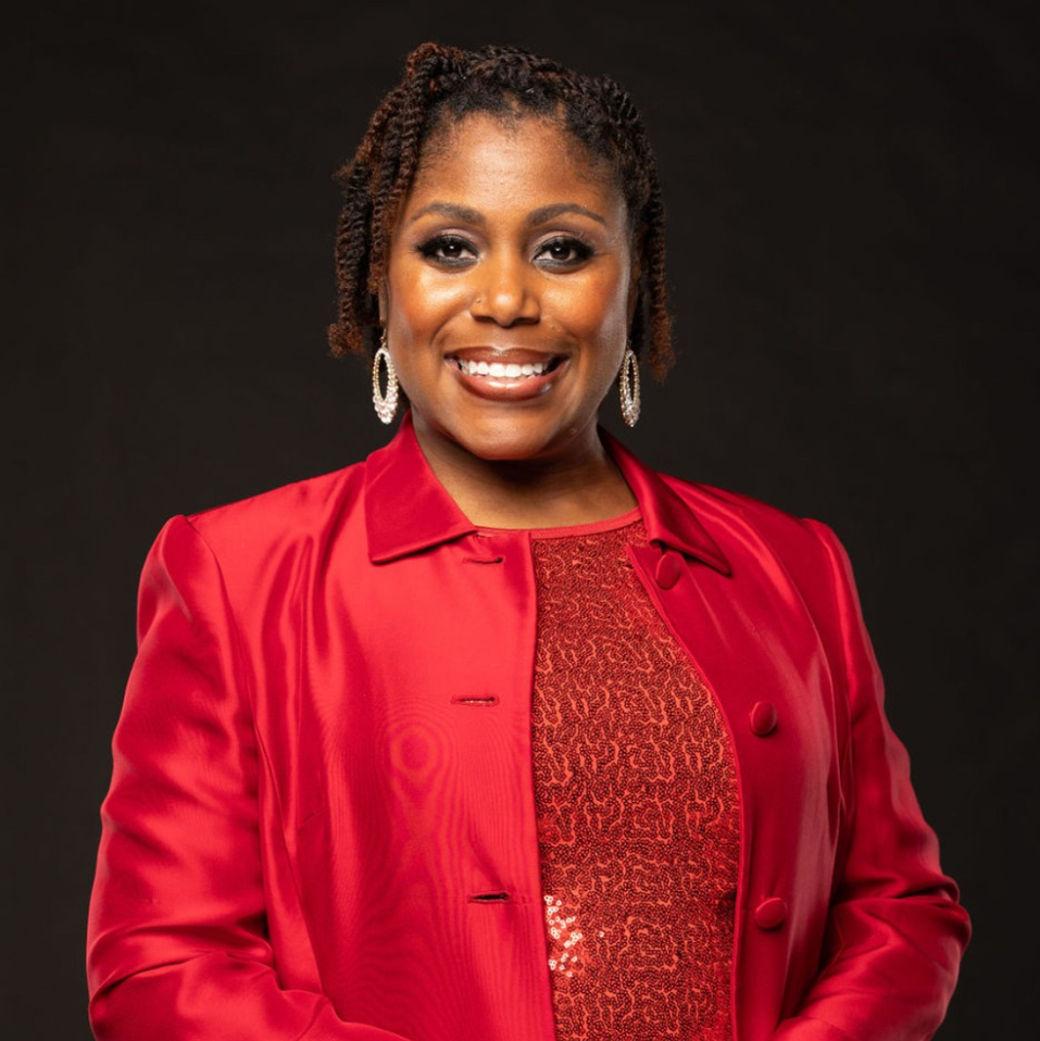 Portrait of Shondra L. Marshall, PhD. She's starting against a dark background in a bright red suit and is smiling.