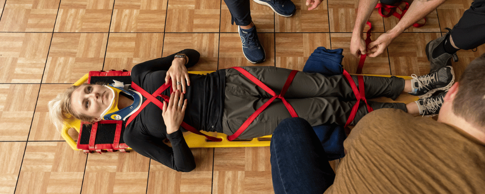 Karmyn Polakowski on a gurney at Marquette Mountain Resort. By her side, fellow medical students conducting a mock emergency scenario.