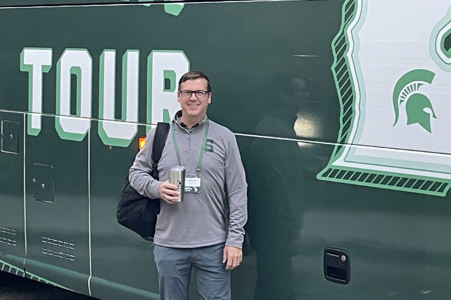 Jeff MacKeigan standing in front of the Spartan Bus Tour bus.