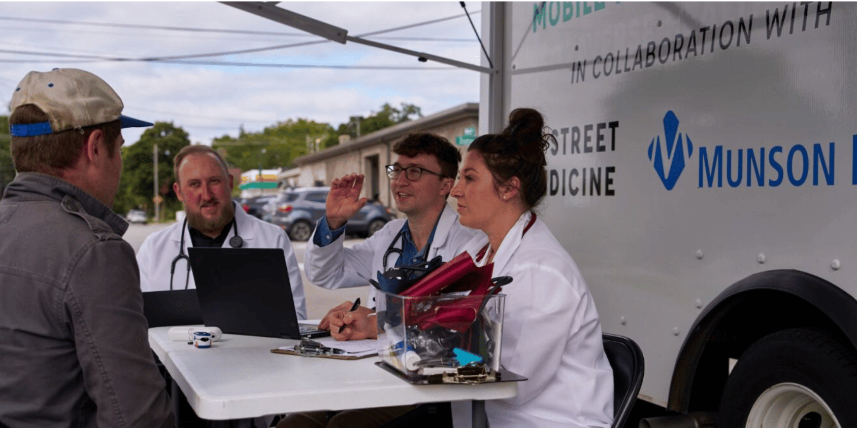 Students consulting a patient in front of the mobile health unit.