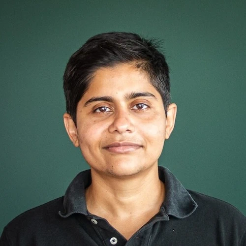  Portrait of Megh Marathe posing in front of a green wall.