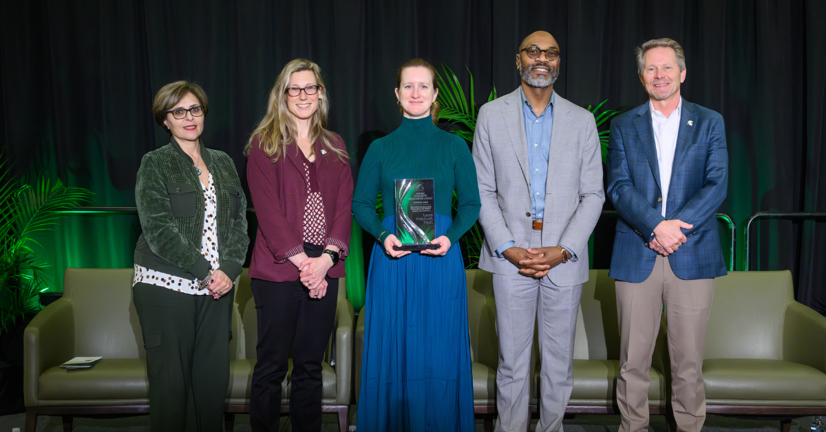 Laura Freidhoff, MD, standing center with the award, with people on either side of her.