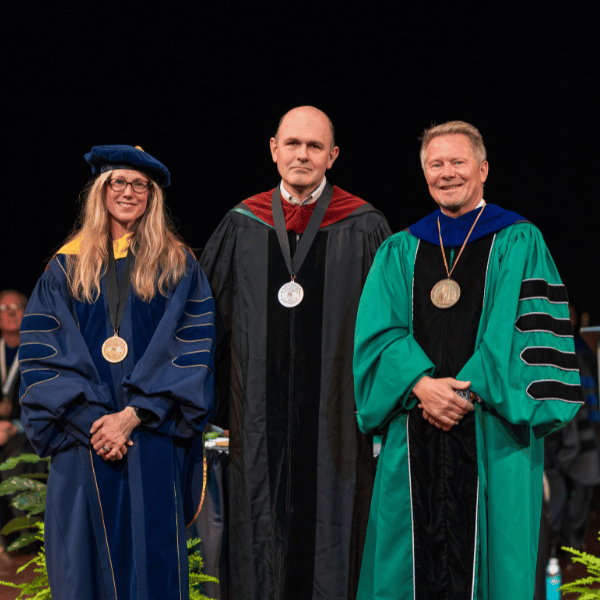 Cristian Meghea, center, with the provost and president at the 2026 investiture.