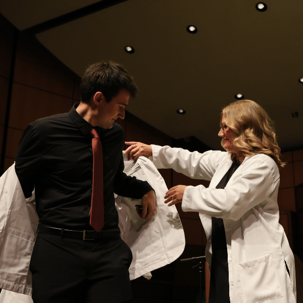 Tammy LaRue coating her son Jon LaRue at the Michigan State University College of Human Medicine White Coat ceremony.