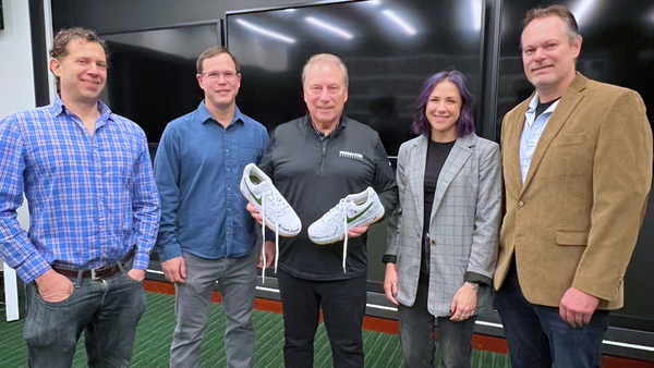 Todd Lucas, PhD, and Olivia Aspiras, PhD, both from the Charles Stewart Mott Department of Public Health, and Eran Andrechek, PhD, Department of Physiology, with Tom Izzo holding the sneakers he will wear for the coaches vs. cancer game.