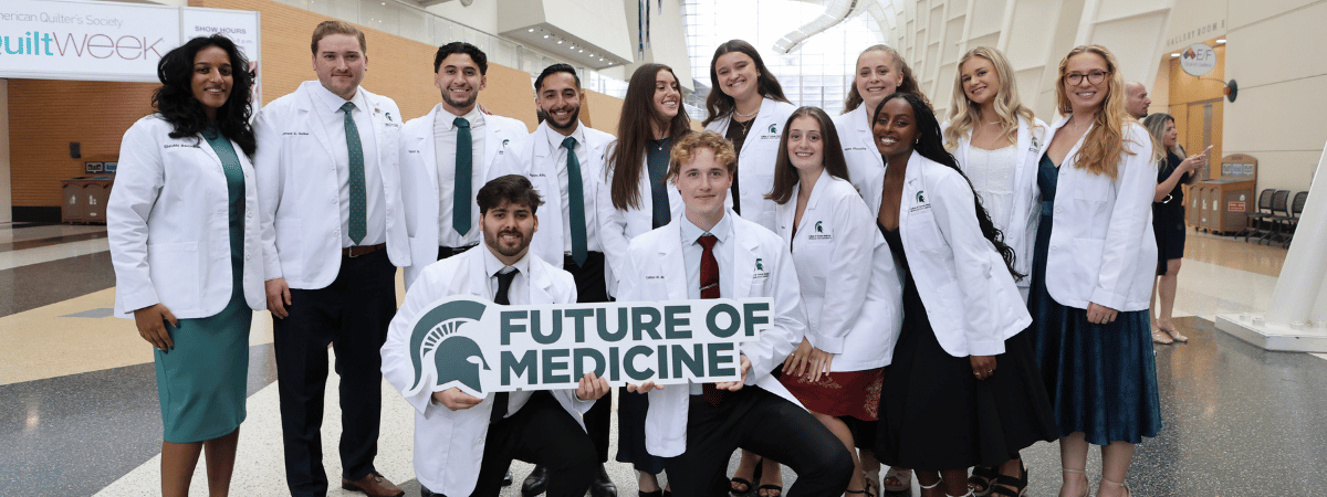 A group of incoming students at the White Coat cermony holding a "future of medicine" sign.