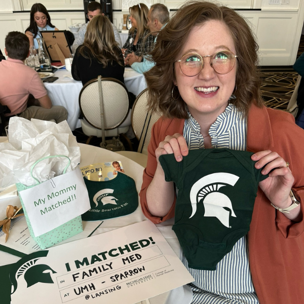 Kelsey Bean holding a Spartan onesie at match day.