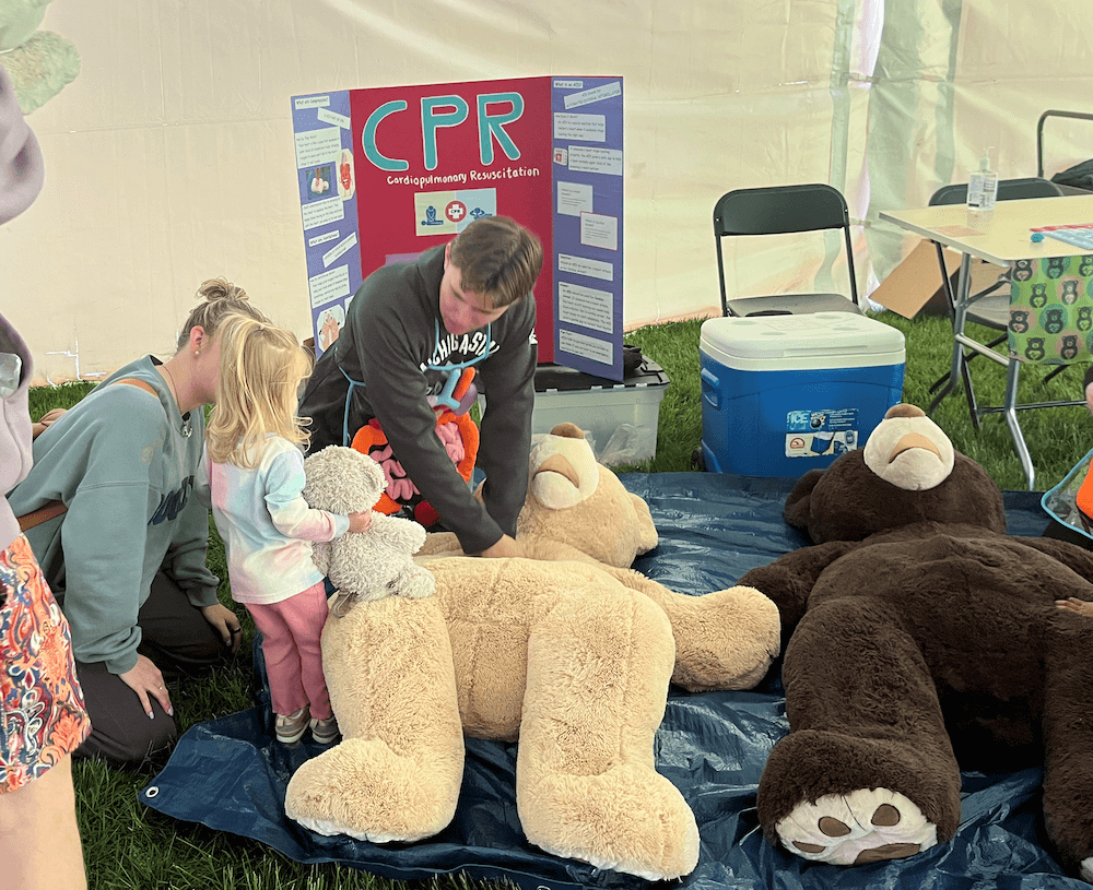 Linden Wells, a Michigan State University undergraduate studying physiology, demonstrates CPR on a large Teddy Bear.