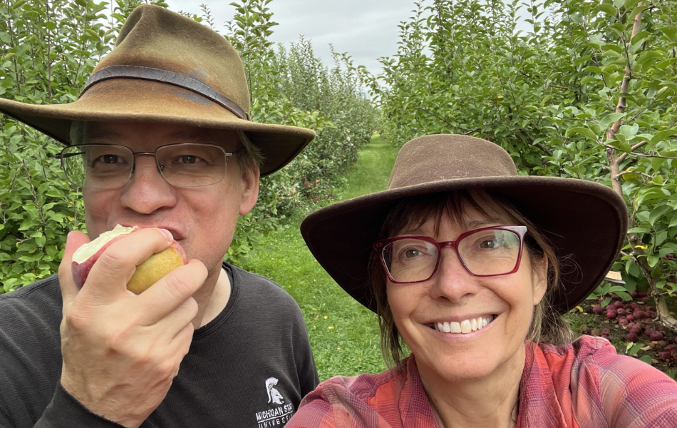 Dean Aron Sousa, eating an apple, standing next to his wife.