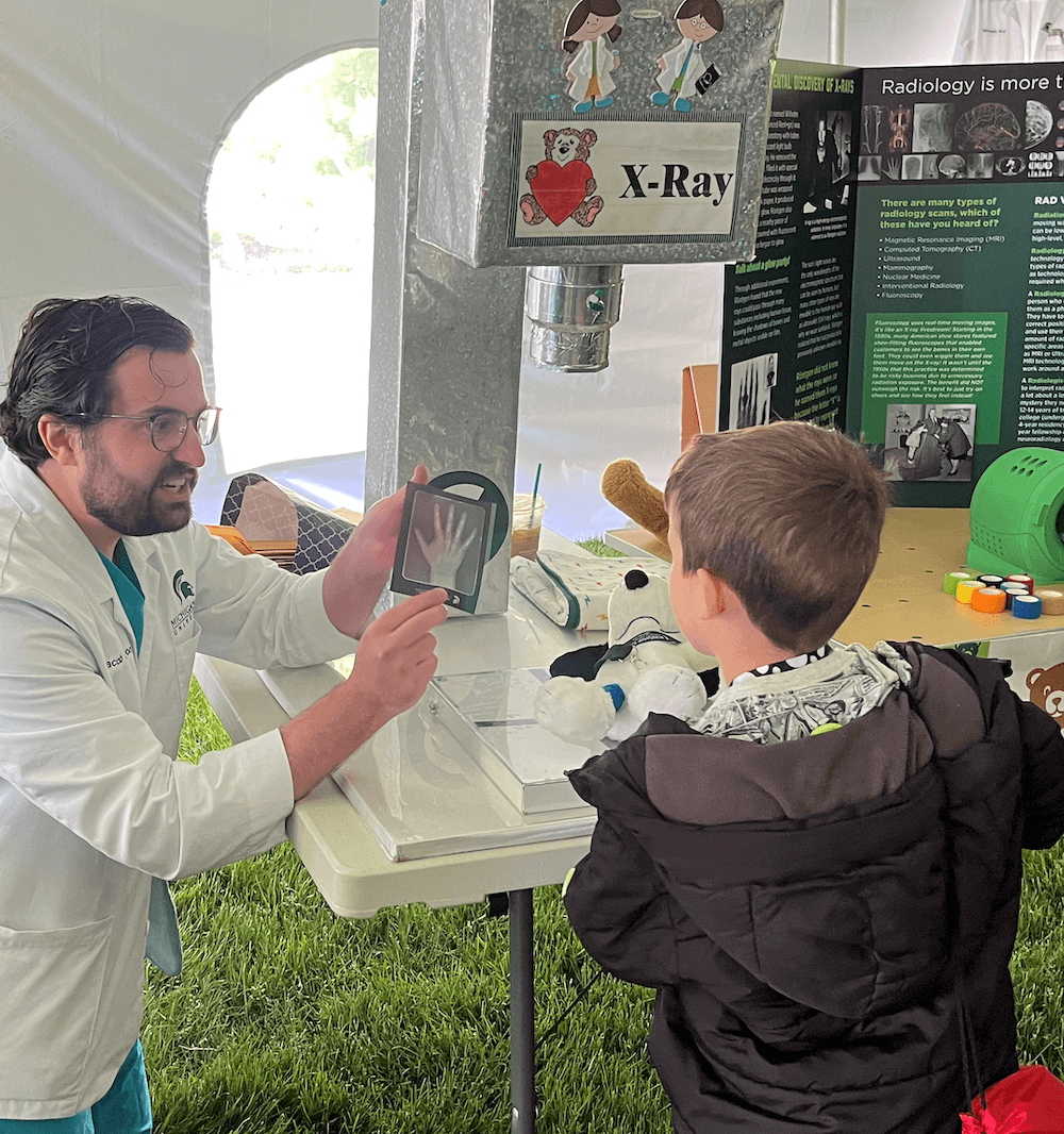 Jacob Charron (MS3) explains an x-ray to the young human of Snoopy.