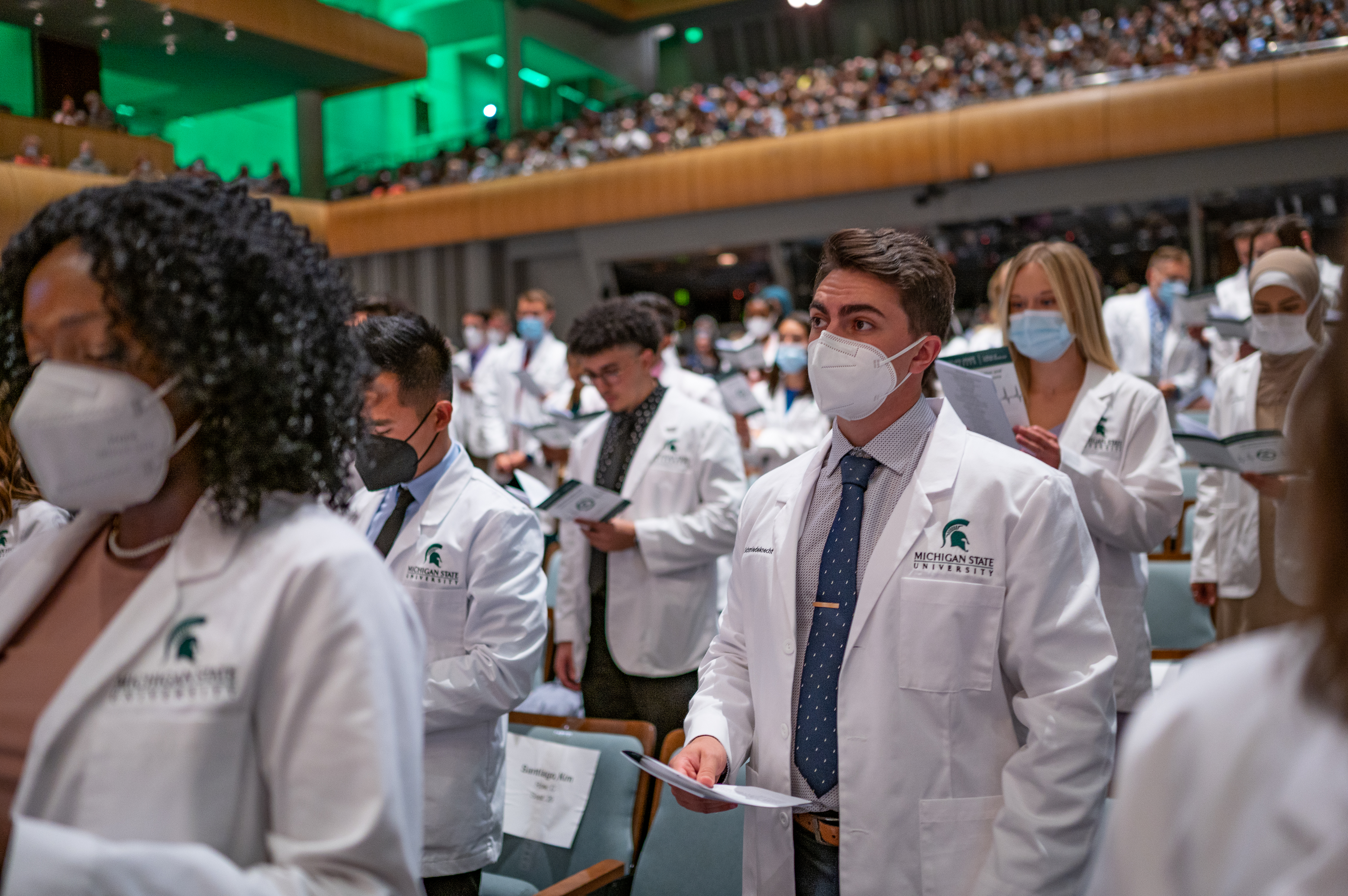 Medical students wearing white coats reading Hippocratic Oath